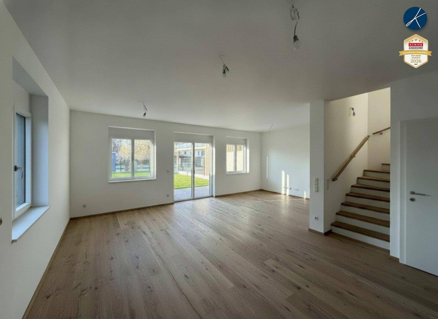Helles Wohnzimmer mit Eichenparkettboden, großen Fenstern und Zugang zum Gartenbereich.
