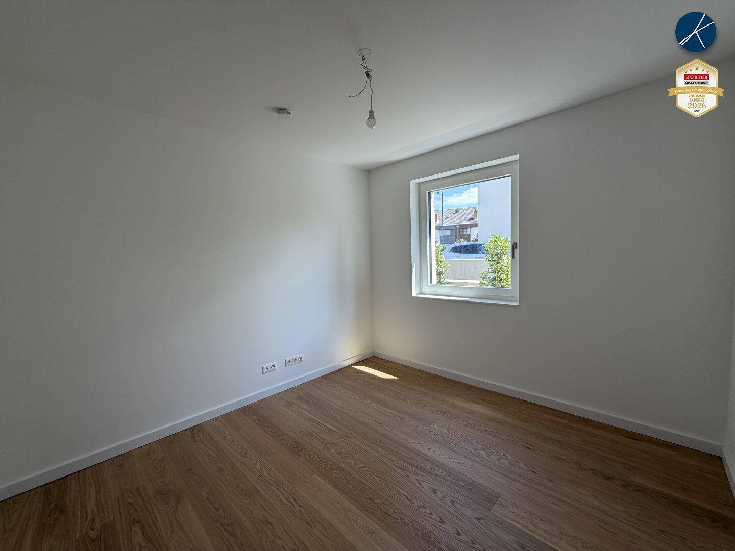 Unmöbliertes Zimmer mit Holzboden und großem Fenster, ideal als Schlafzimmer.