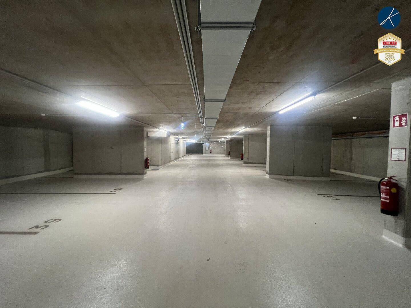 Geräumige Tiefgarage mit Betonwänden und -decken, gut beleuchtet und leer.