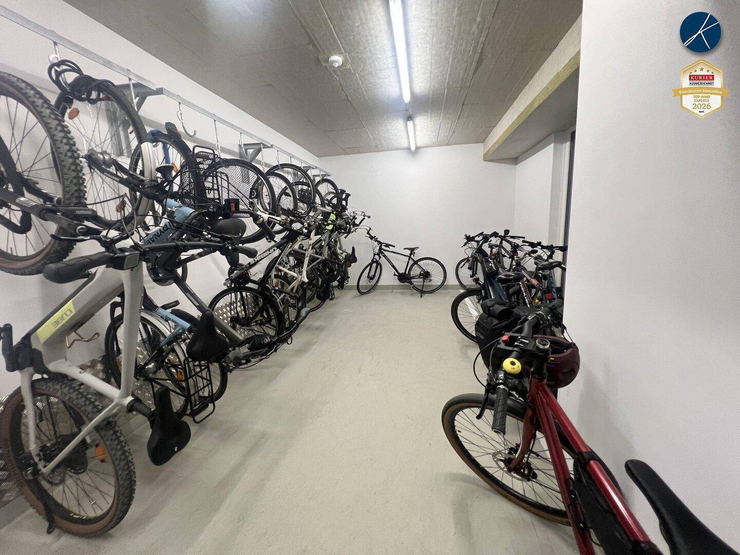 Großer Fahrradraum mit vielen Fahrrädern, die ordentlich an der Wand gelagert werden.
