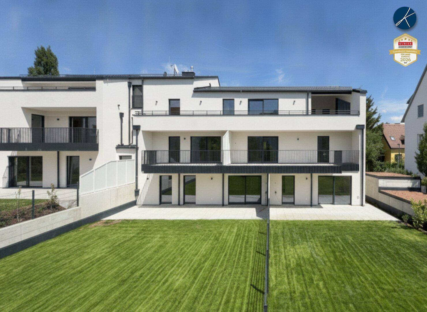 Weitläufige Ansicht des modernen Wohnkomplexes mit Balkonen und großer Grünfläche.