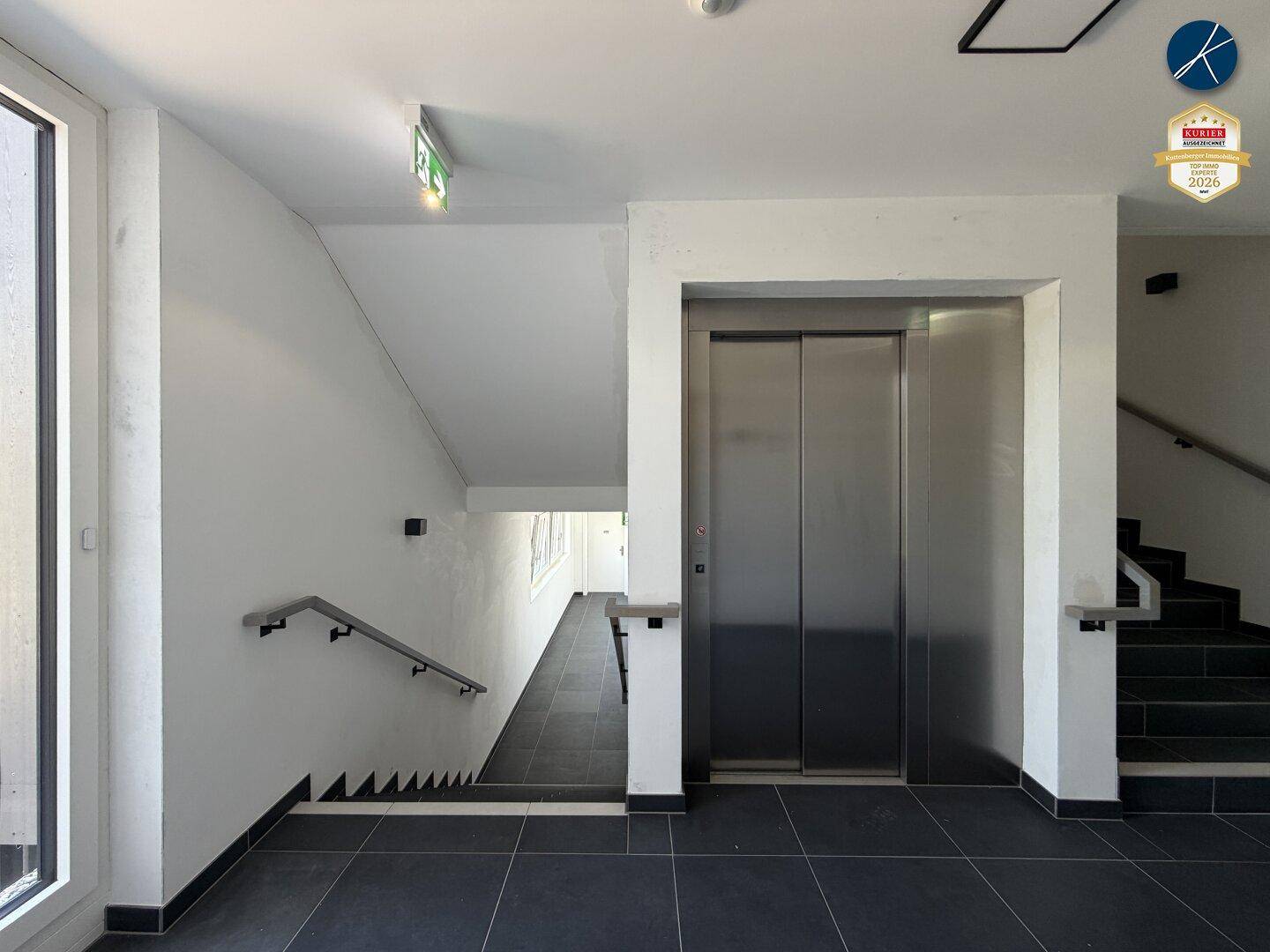 Moderner Eingangsbereich mit Aufzug und Treppenhaus, das zu den Wohneinheiten führt.