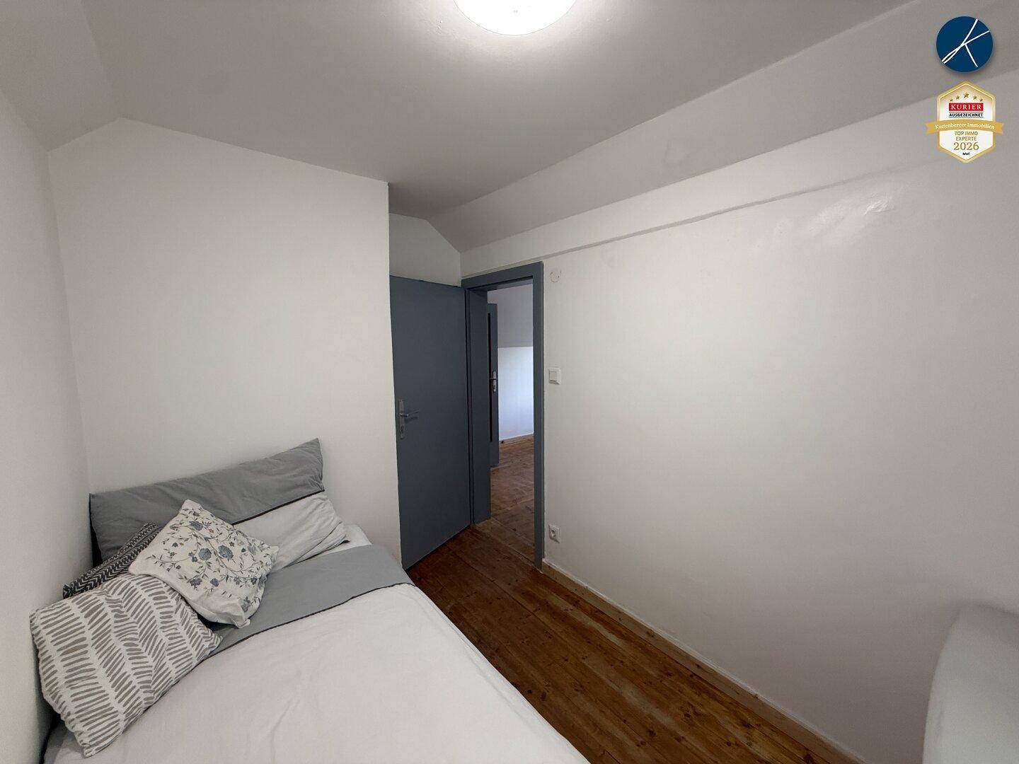 Gemütliches Schlafzimmer mit Holzboden und weiß gestrichenen Wänden.