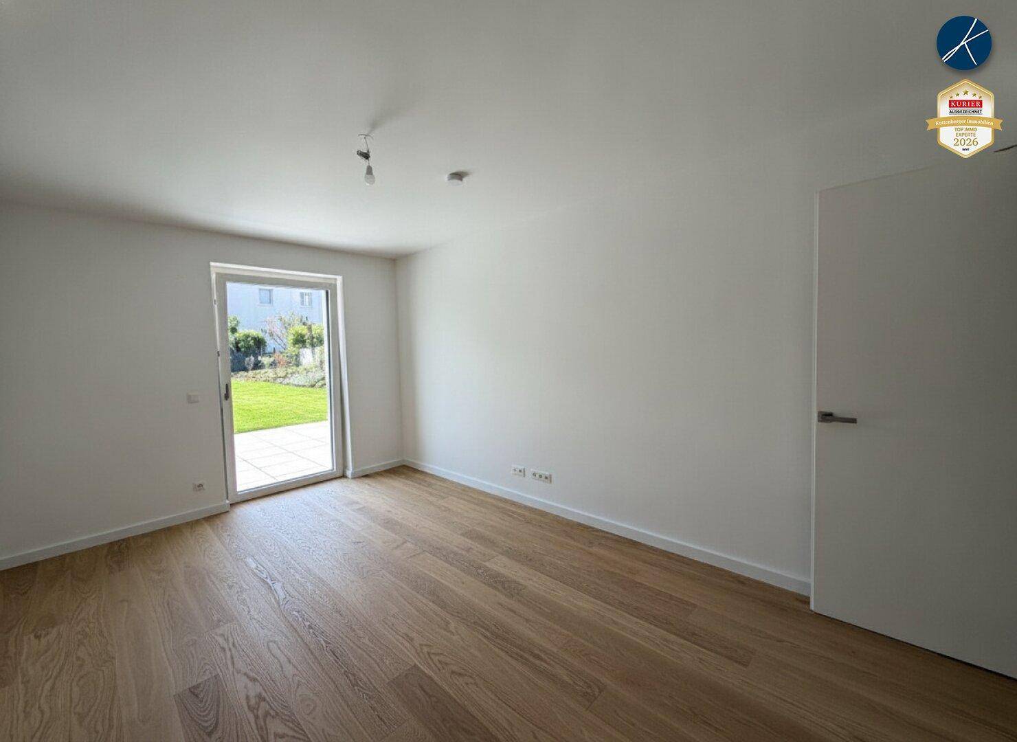 Leeres Zimmer mit Holzboden und Zugang zum Außenbereich, ideal für individuelle Gestaltung.