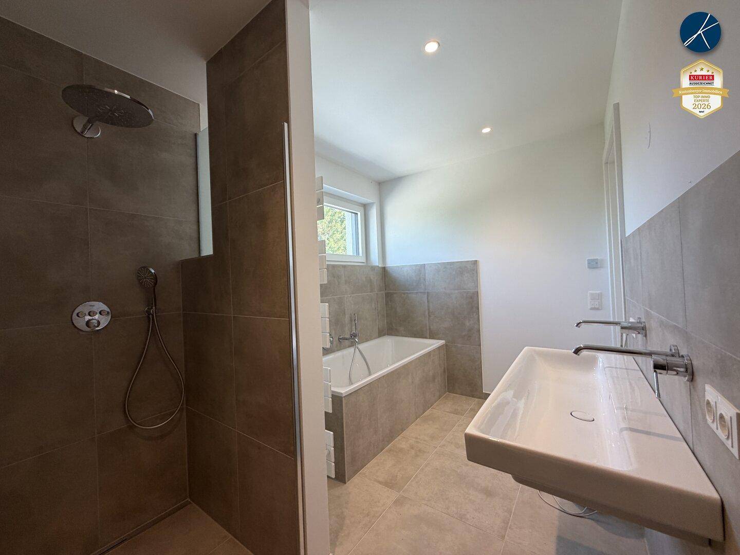 Modernes Badezimmer mit großer Dusche, Badewanne und Doppelwaschbecken in neutralen Farbtönen.