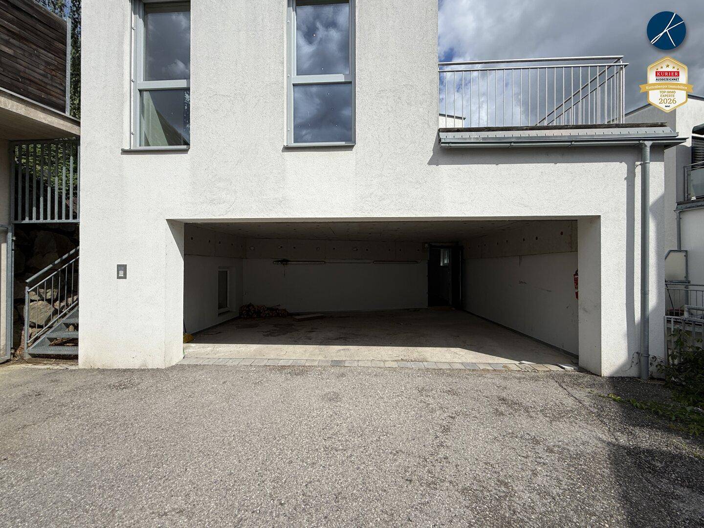 Offene Garagenfläche unter dem Gebäude mit Betonboden und ausreichend Platz für Fahrzeuge.
