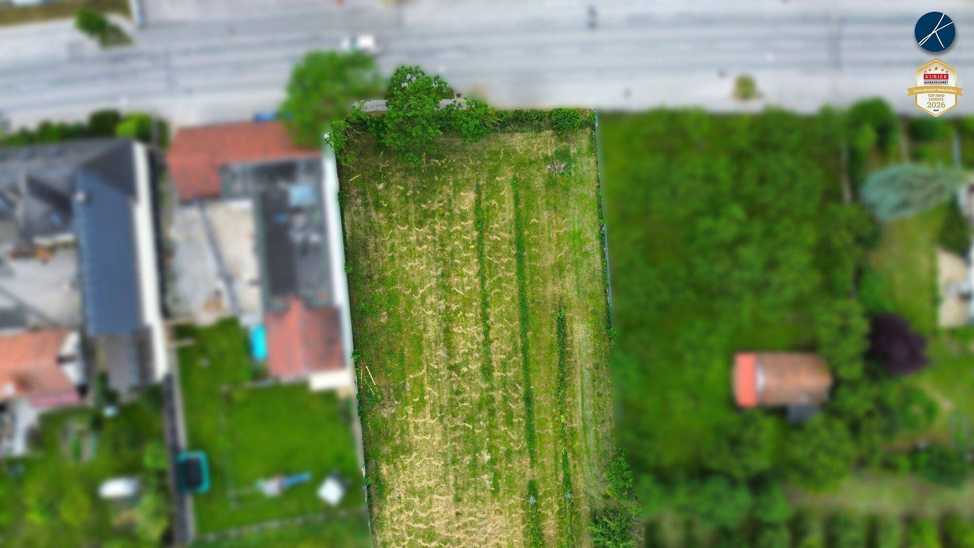 Luftaufnahme eines grünen Grundstücks mit angrenzenden Häusern und Straßen in ländlicher Umgebung.