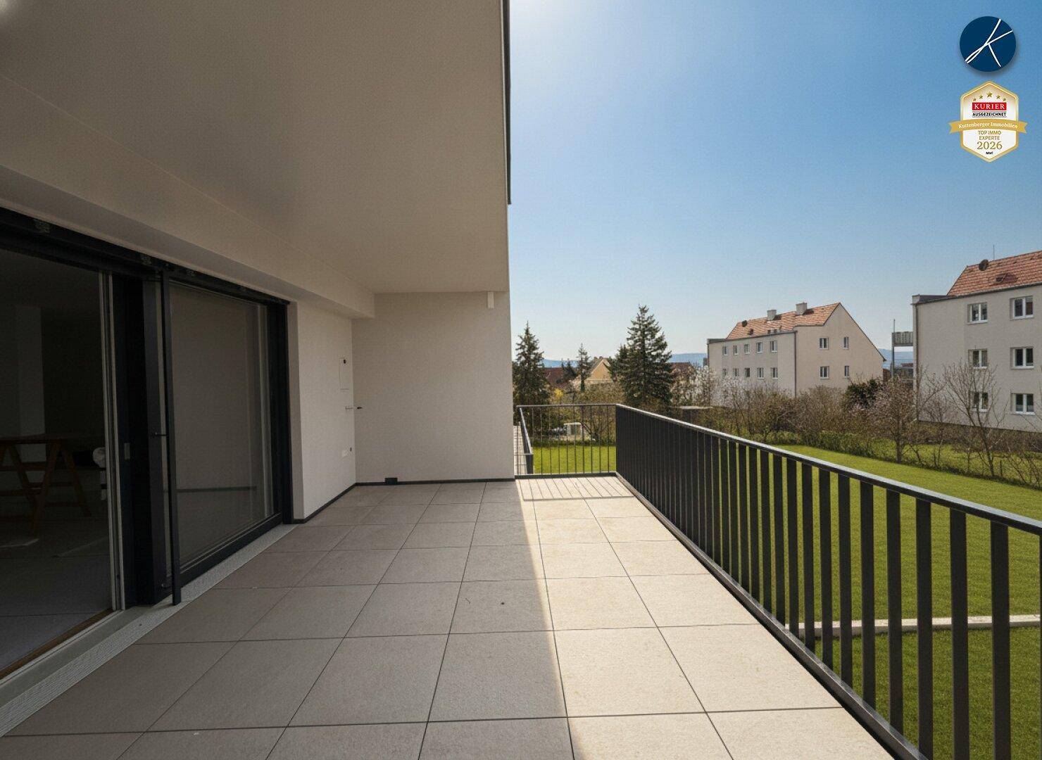 Geräumiger Balkon mit Fliesenboden und Blick auf die umliegende Wohngegend und Grünflächen.