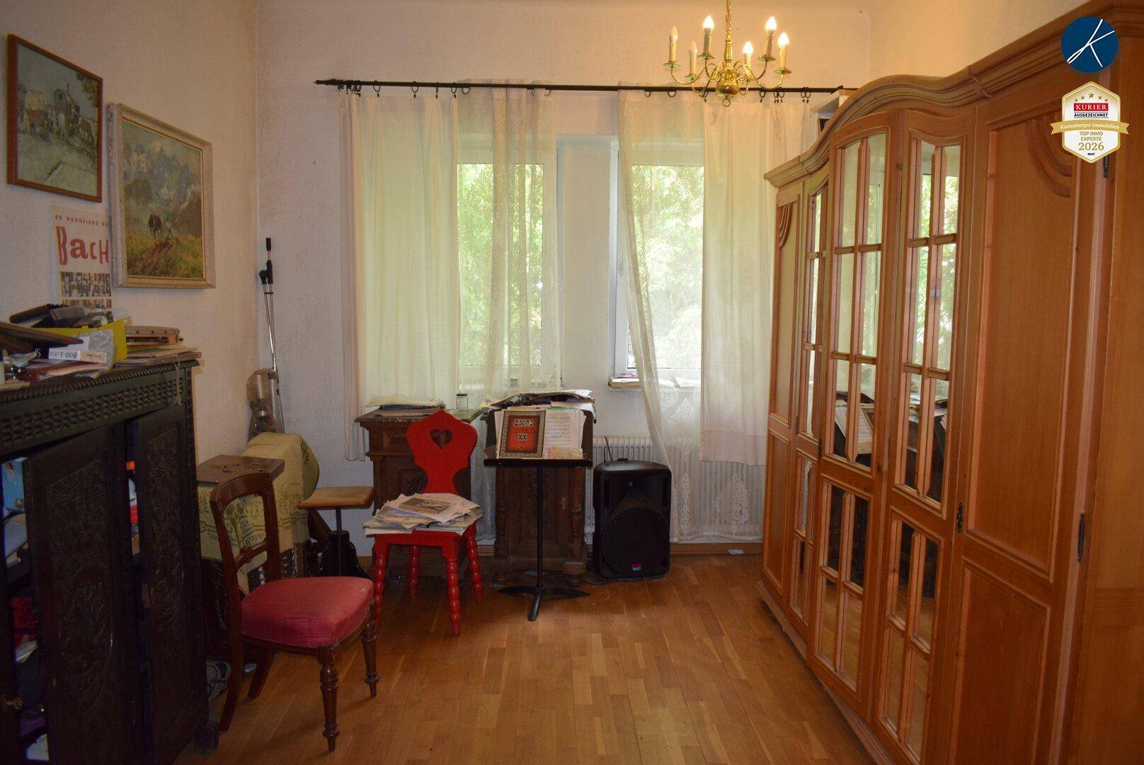 Helles Zimmer mit Holzboden, großem Kleiderschrank und Fenstern mit Blick ins Grüne.