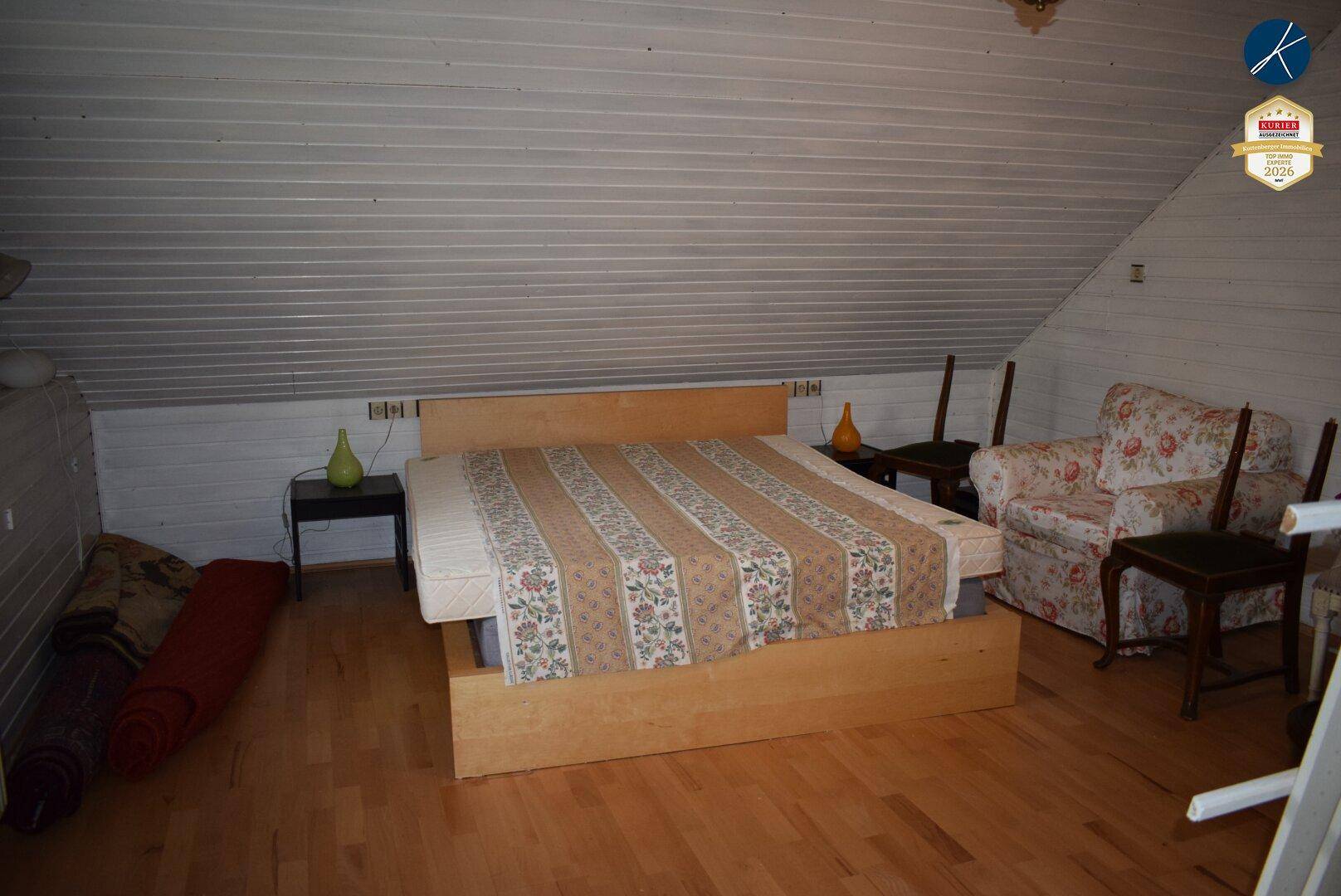 Geräumiges Schlafzimmer im Dachgeschoss mit Holzboden und schrägen Wänden.