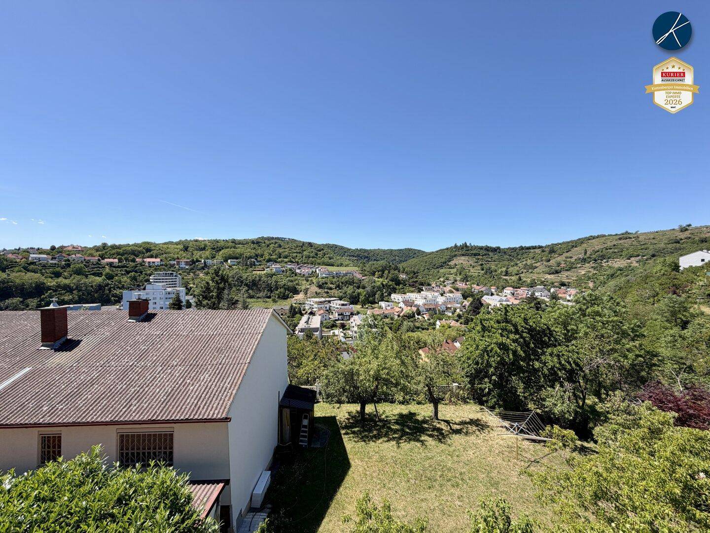 Weitläufiger Blick über die grüne Hügellandschaft und eine ländliche Siedlung.