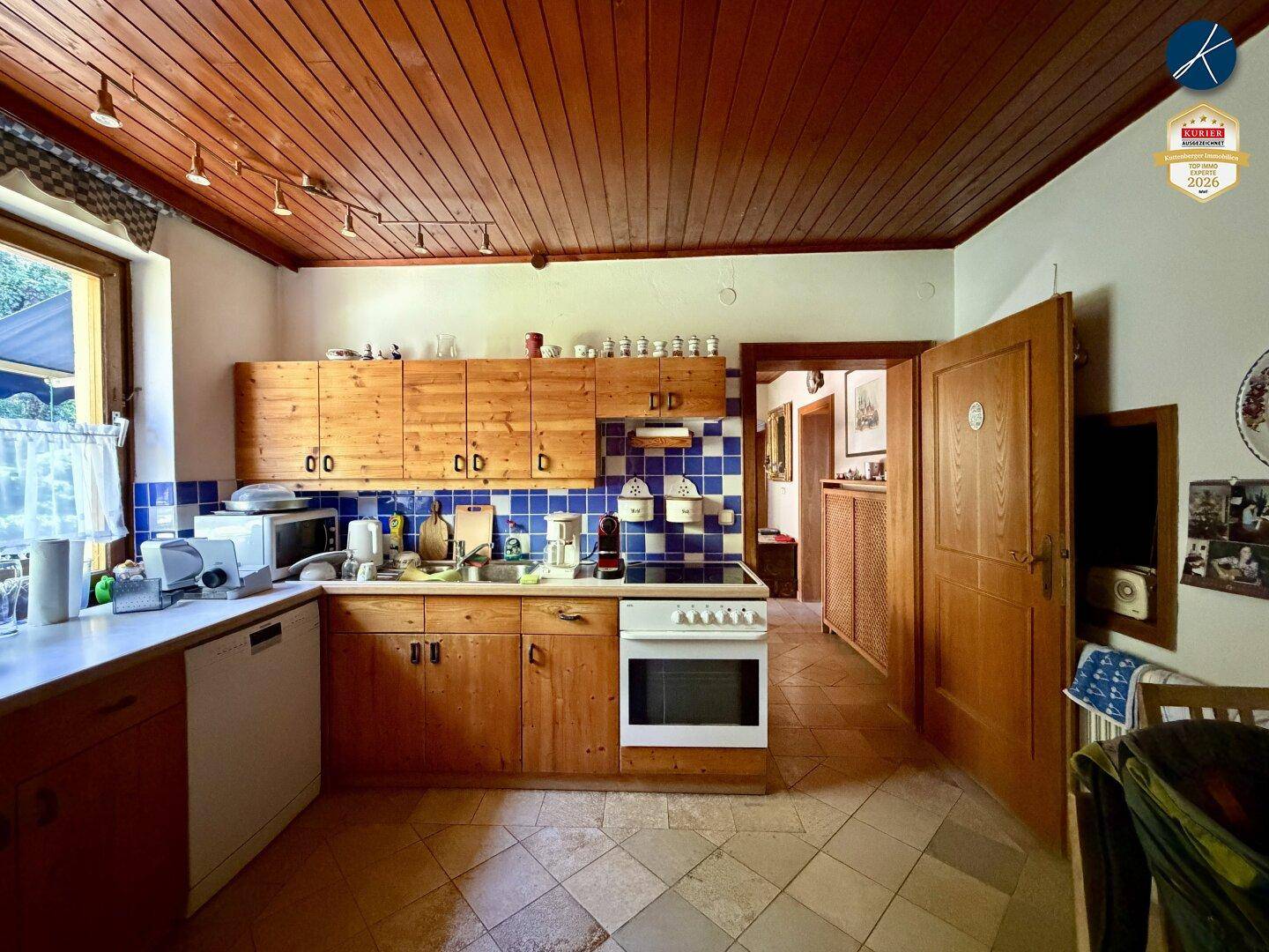 Traditionelle Holzküche mit blauen Fliesen, Einbaugeräten und gefliestem Boden.