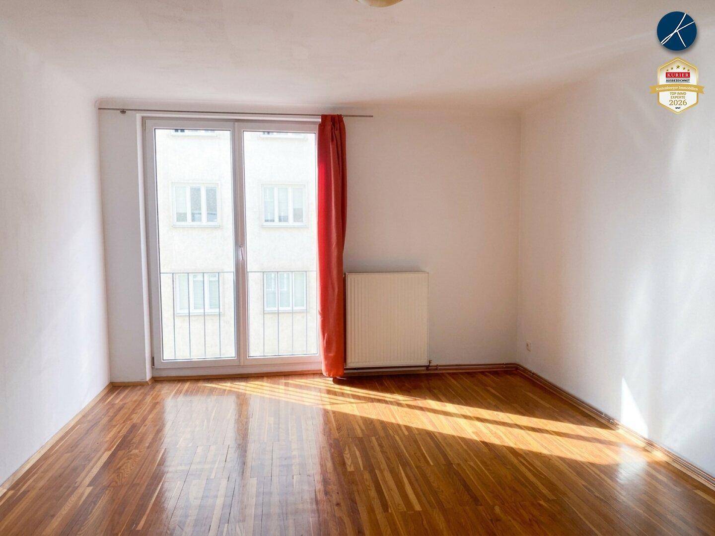 Helles Zimmer mit Parkettboden und Zugang zu einem französischen Balkon, der viel Licht spendet.