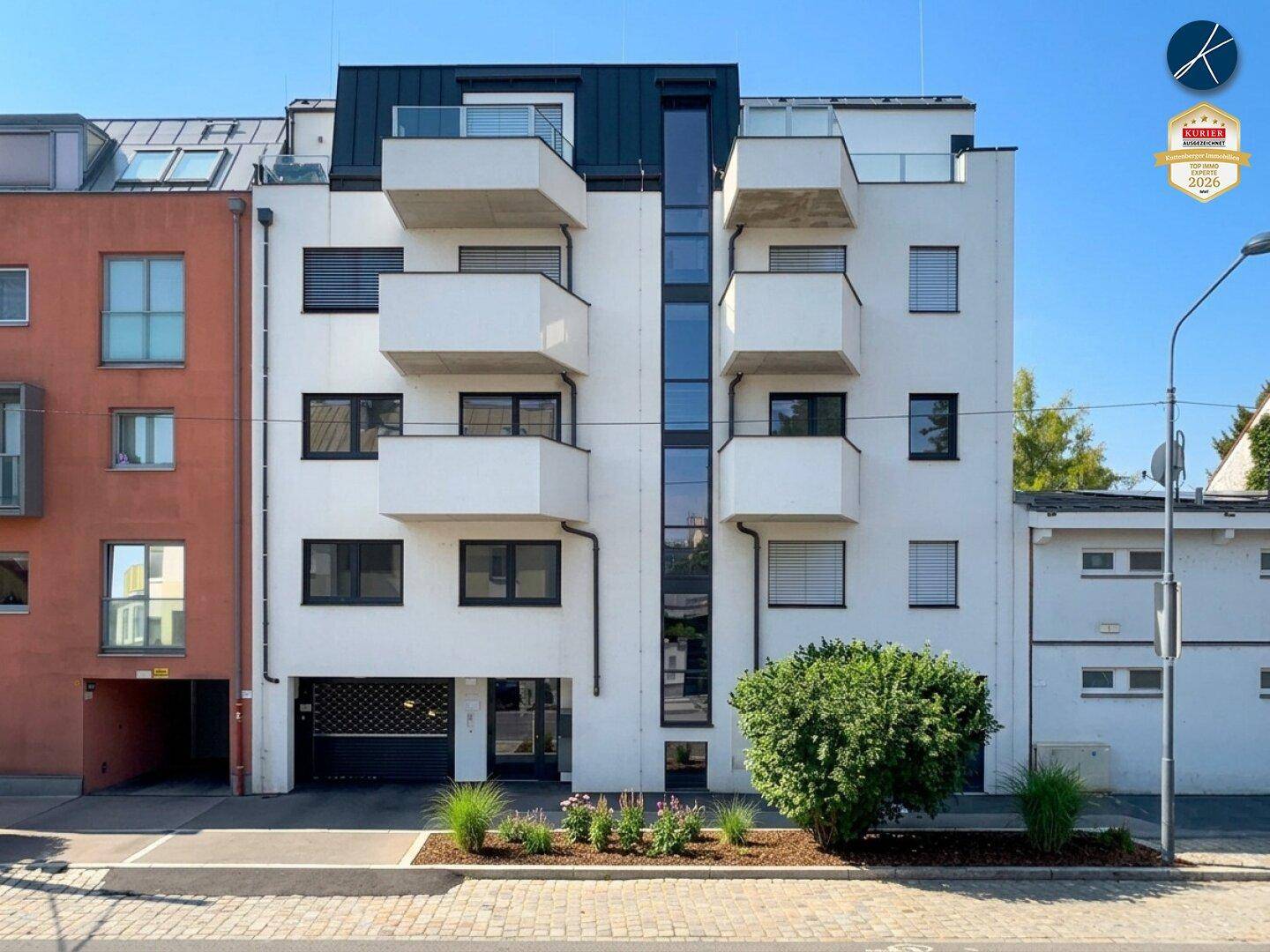 Moderne Wohnhausfassade mit mehreren Balkonen und großen Fenstern in einem städtischen Umfeld.