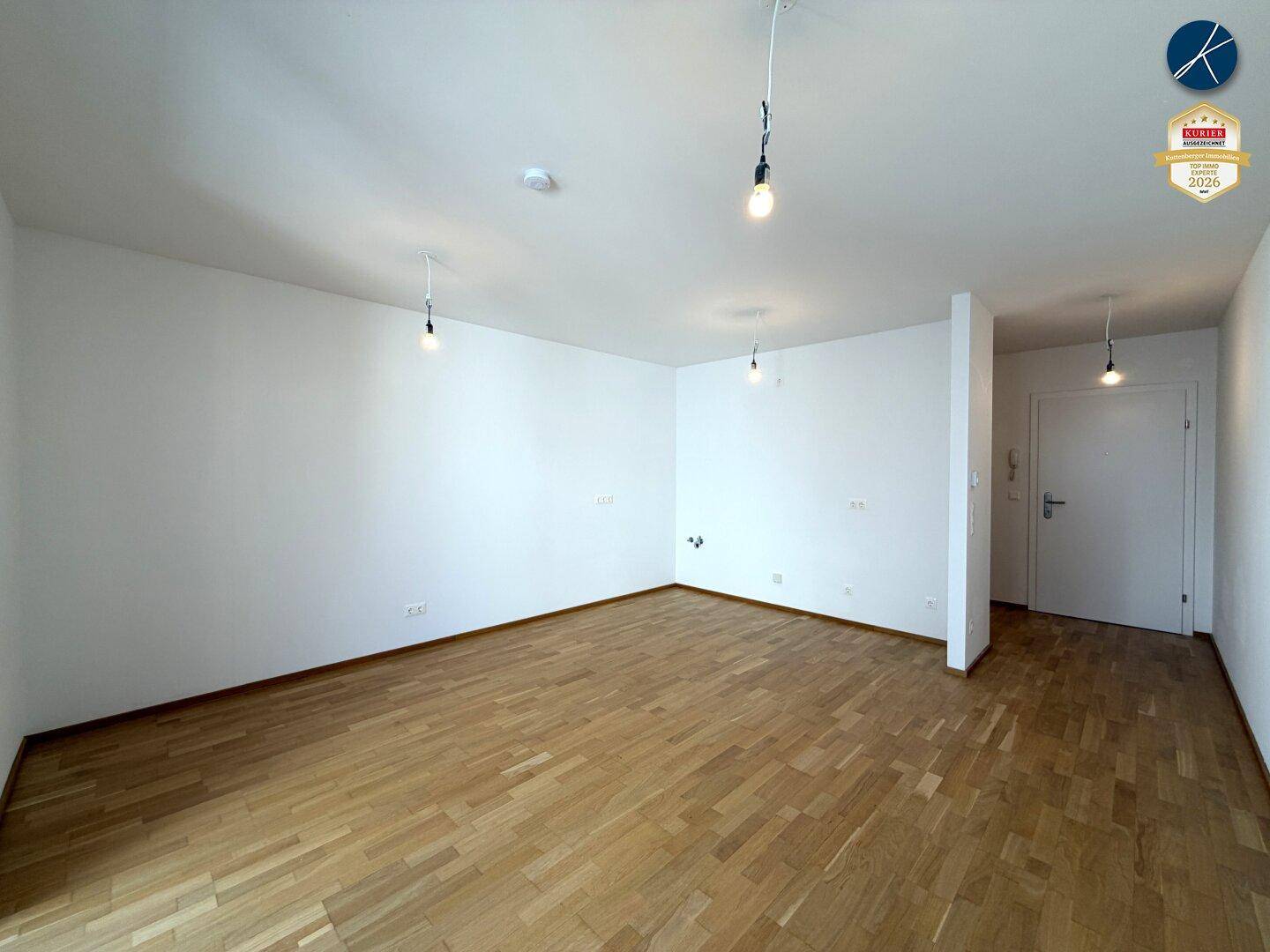 Geräumiges Wohnzimmer mit hellem Parkettboden und weißen Wänden, bereit zur individuellen Gestaltung.