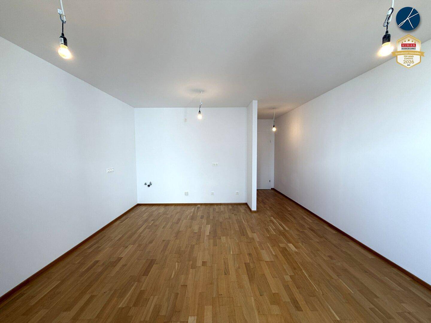 Weitläufiges Wohnzimmer mit Parkettboden und minimalistischer Beleuchtung, ideal für modernes Wohnen.