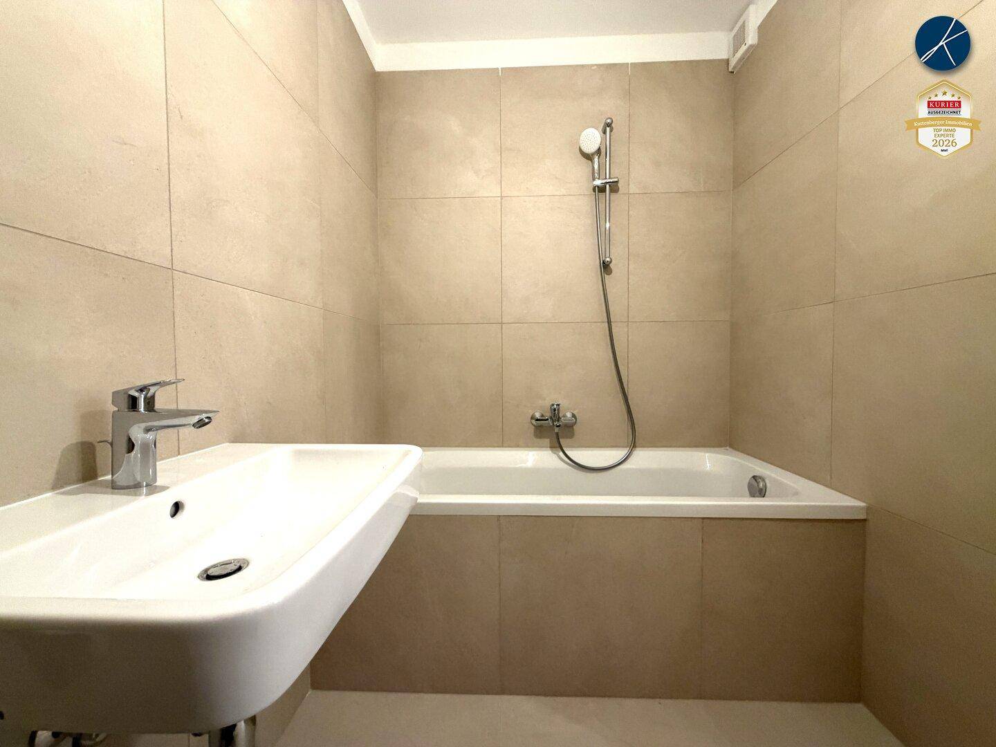 Badezimmer mit Badewanne und Duschfunktion, ausgestattet mit einem modernen Waschbecken und Armaturen.