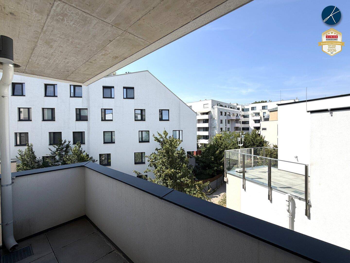 Geräumiger Balkon mit Blick auf die umliegenden modernen Wohngebäude und Grünflächen.