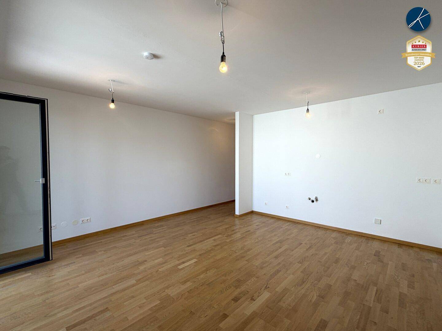 Weitläufiges, unmöbliertes Zimmer mit hellem Parkettboden und weißen Wänden, bereit zum Einzug.
