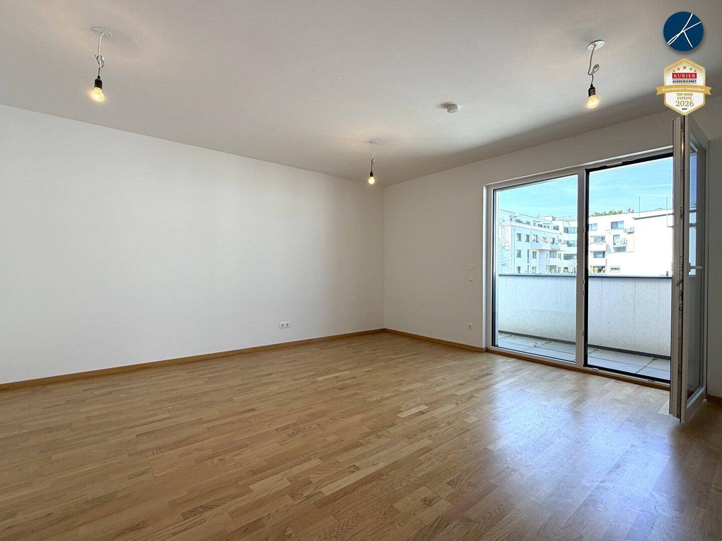 Geräumiges, unmöbliertes Zimmer mit Parkettboden und Zugang zu einem sonnigen Balkon.