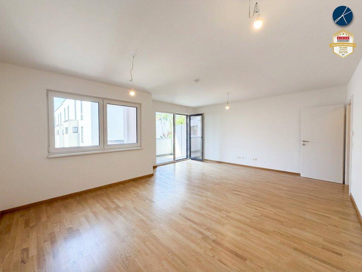 Geräumiges, helles Wohnzimmer mit Holzparkett und Zugang zum Balkon, bereit für individuelle Gestaltung.