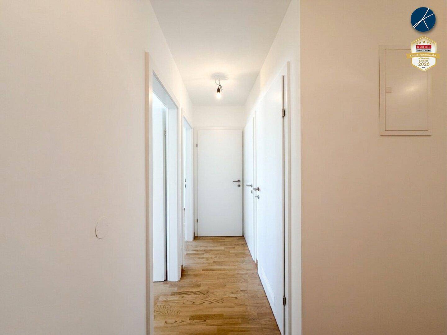 Heller Flur mit Holzparkettboden, der zu den verschiedenen Zimmern der Wohnung führt.
