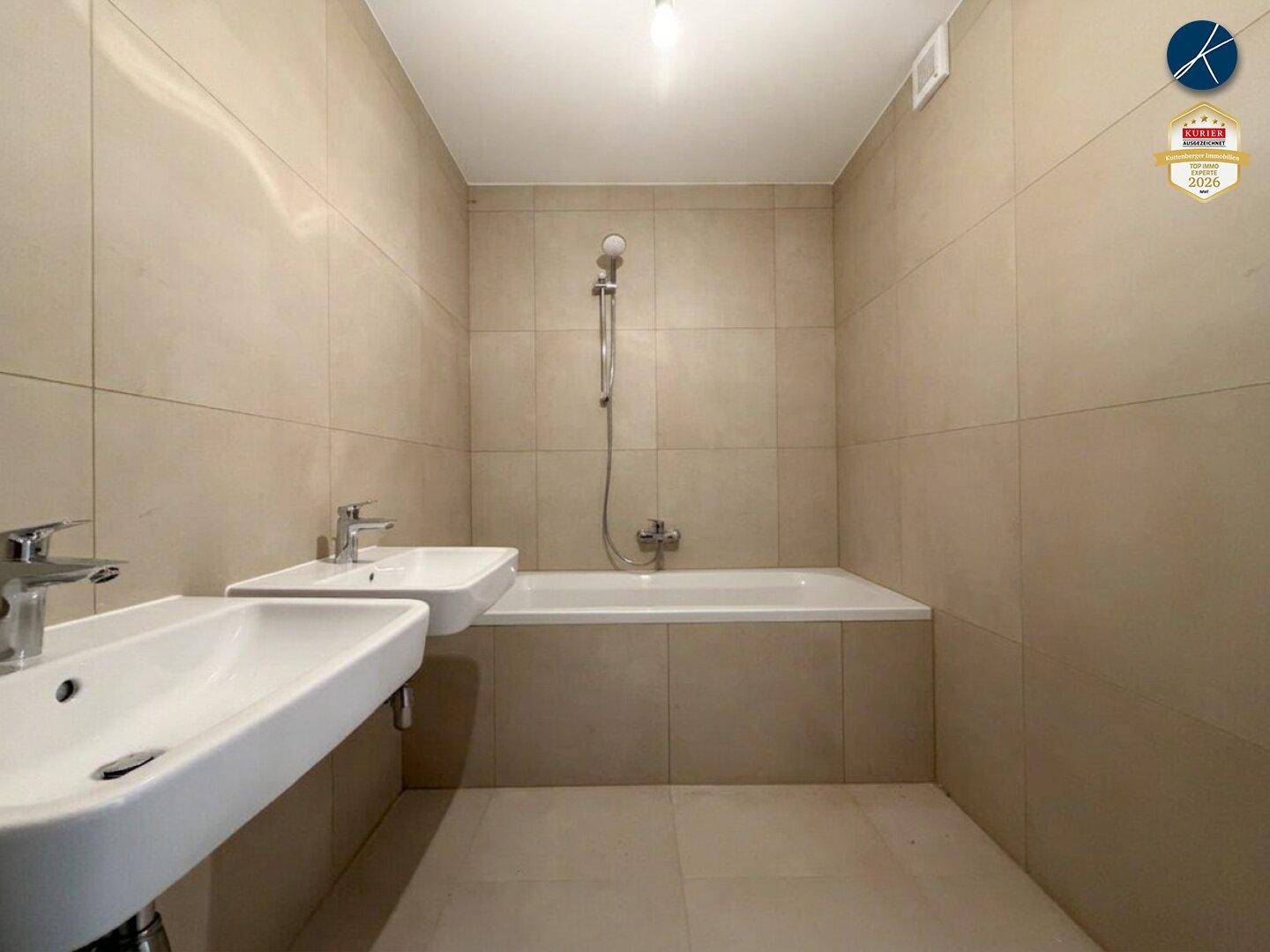 Modernes Badezimmer mit beigefarbenen Fliesen, Badewanne und zwei Waschbecken.