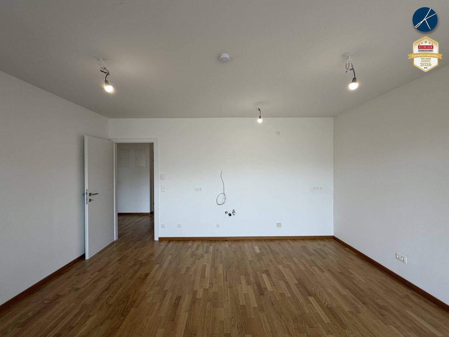 Leeres Zimmer mit hellem Parkettboden und weißen Wänden, bereit für individuelle Gestaltung.