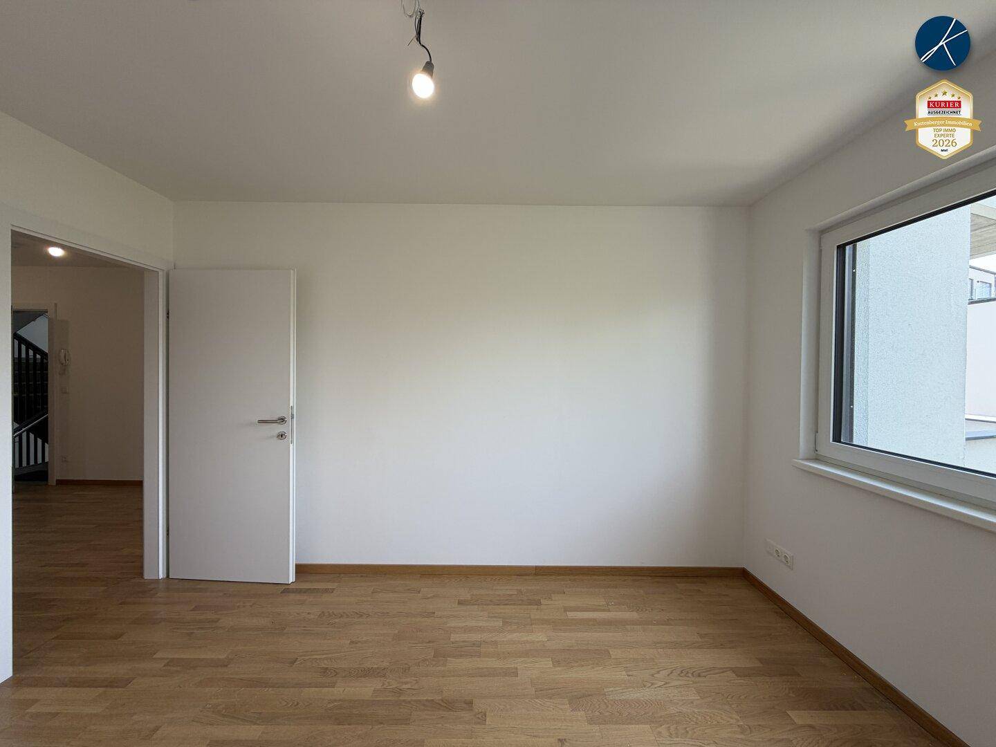 Leeres Zimmer mit hellem Parkettboden und weißen Wänden, bereit für individuelle Gestaltung.