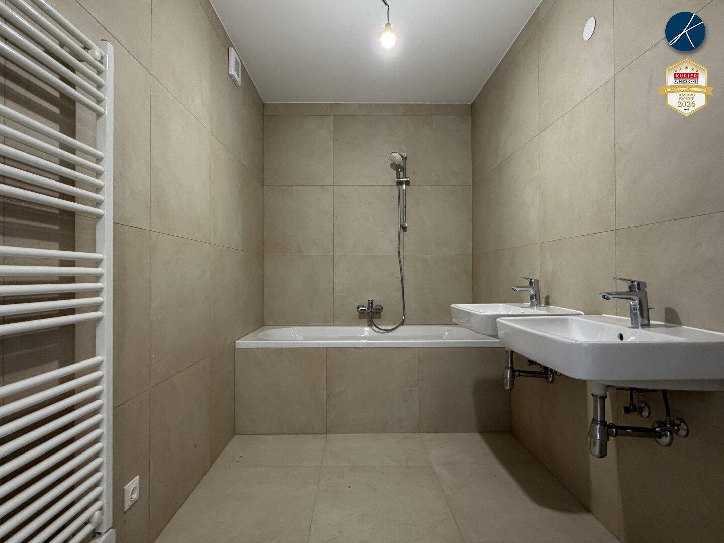 Modernes Badezimmer mit beigefarbenen Fliesen, Badewanne, Dusche und zwei Waschbecken.