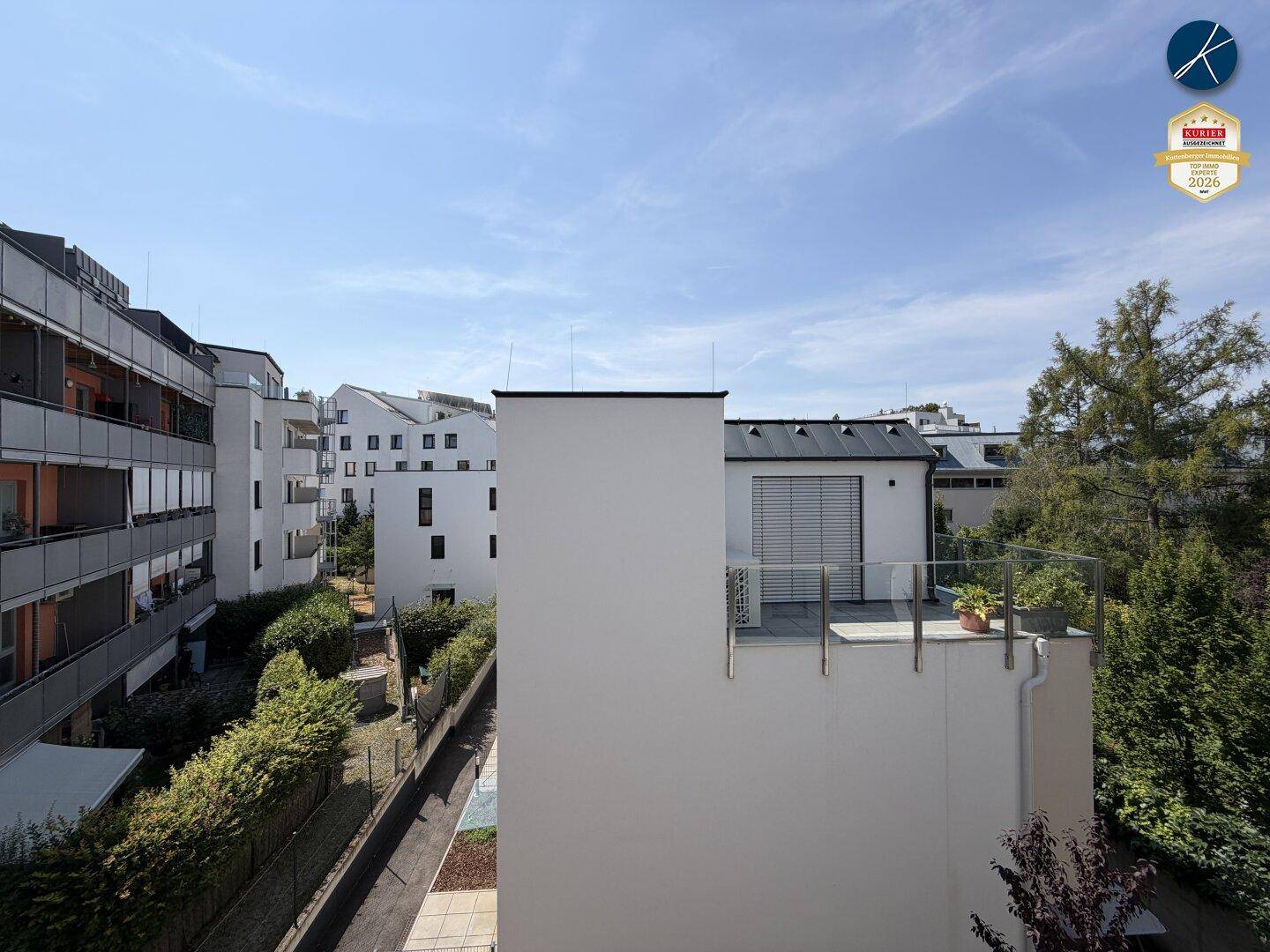 Blick auf moderne Wohngebäude mit Balkonen und grüner Umgebung unter blauem Himmel.