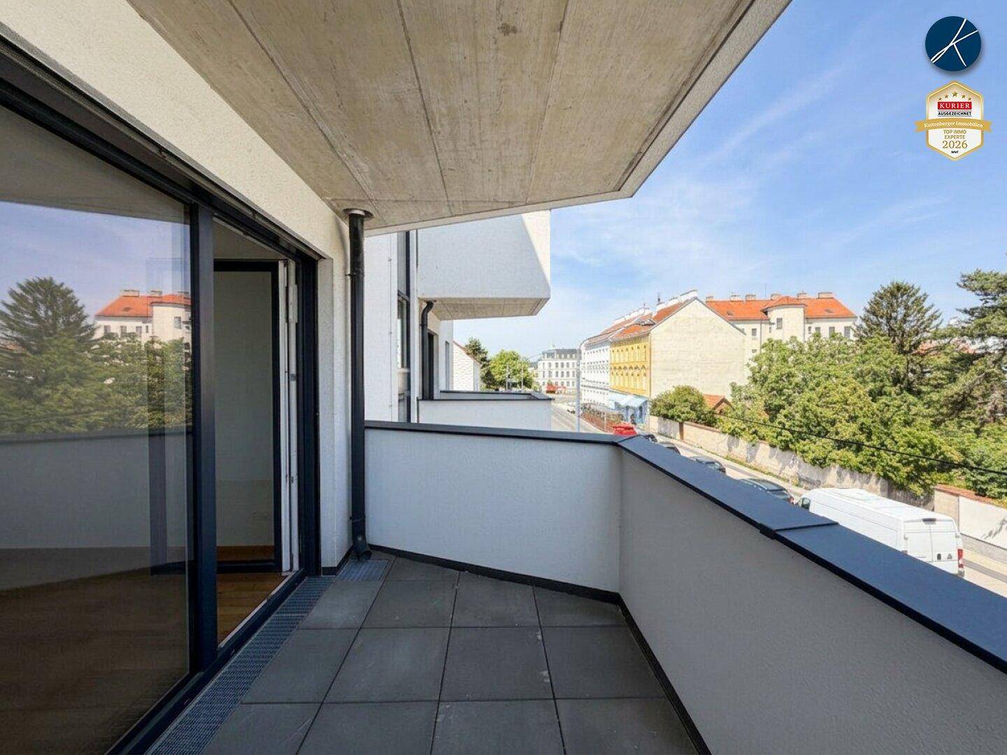 Balkon mit Fliesenboden und Blick auf die Straße und umliegende Gebäude.