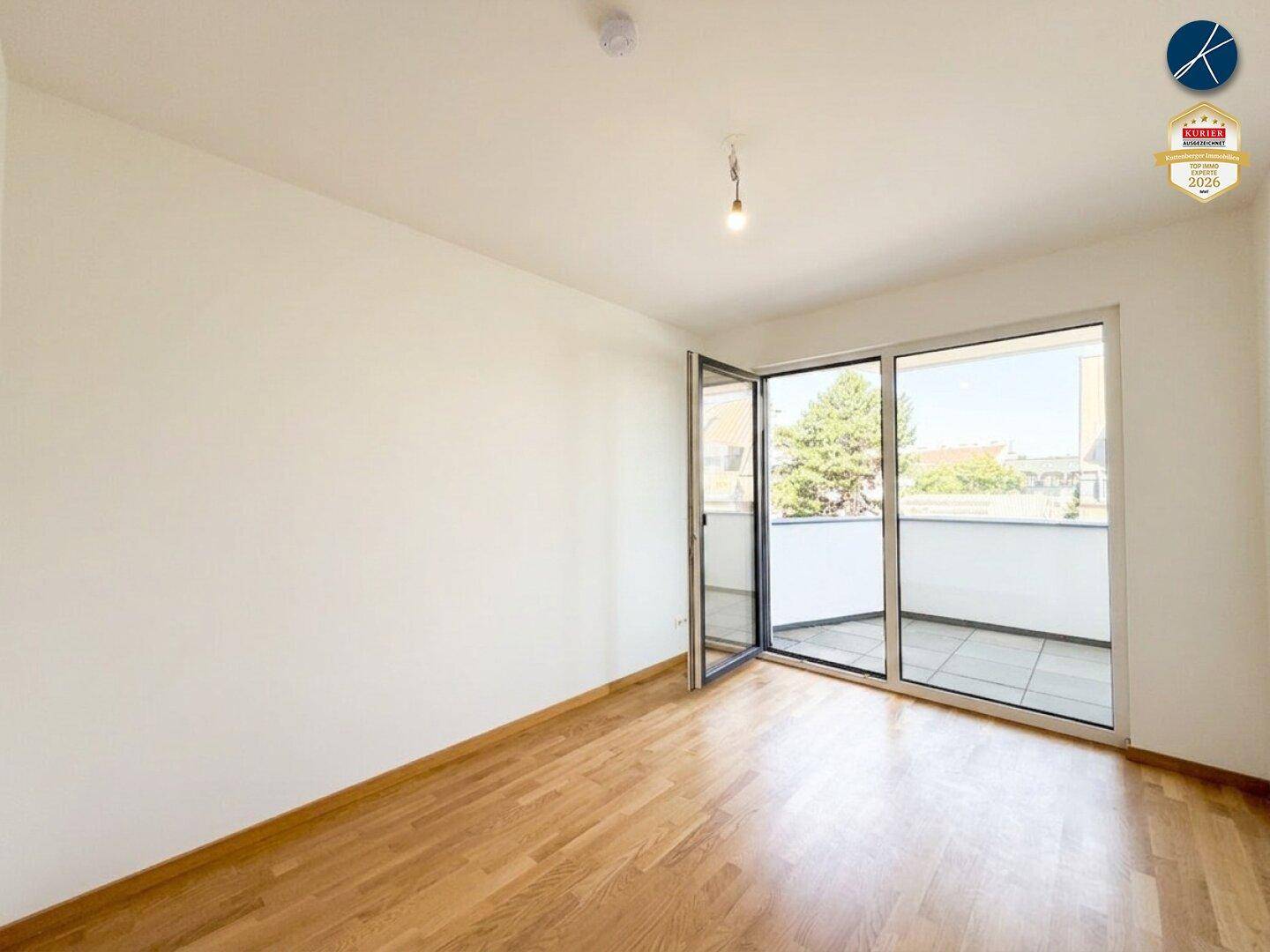 Leeres Zimmer mit Holzparkett und Zugang zu einem Balkon, ideal als Schlaf- oder Arbeitszimmer.