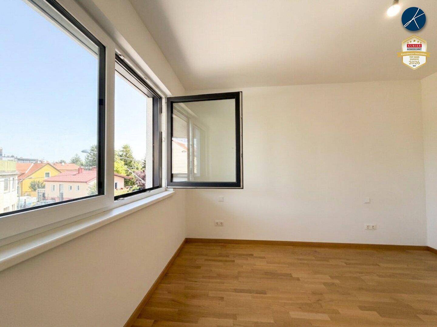 Heller Raum mit Holzparkett und großen Fenstern, die einen weiten Blick ermöglichen.