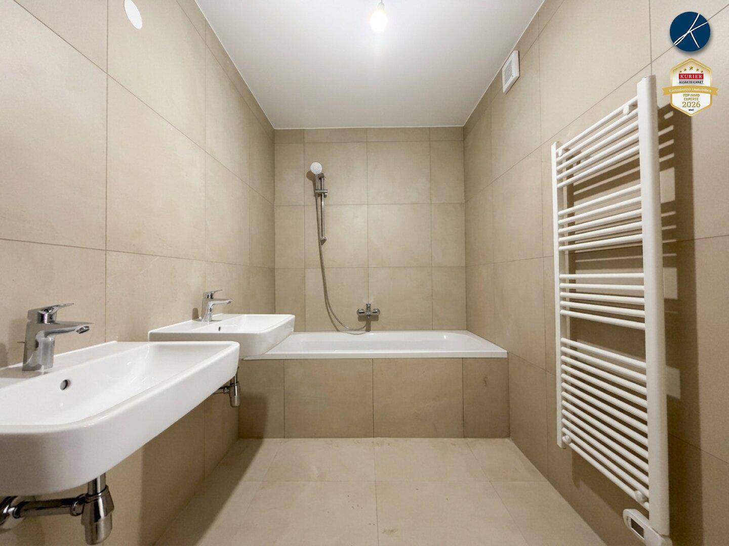 Modernes Badezimmer mit zwei Waschbecken, Badewanne und beheiztem Handtuchhalter.