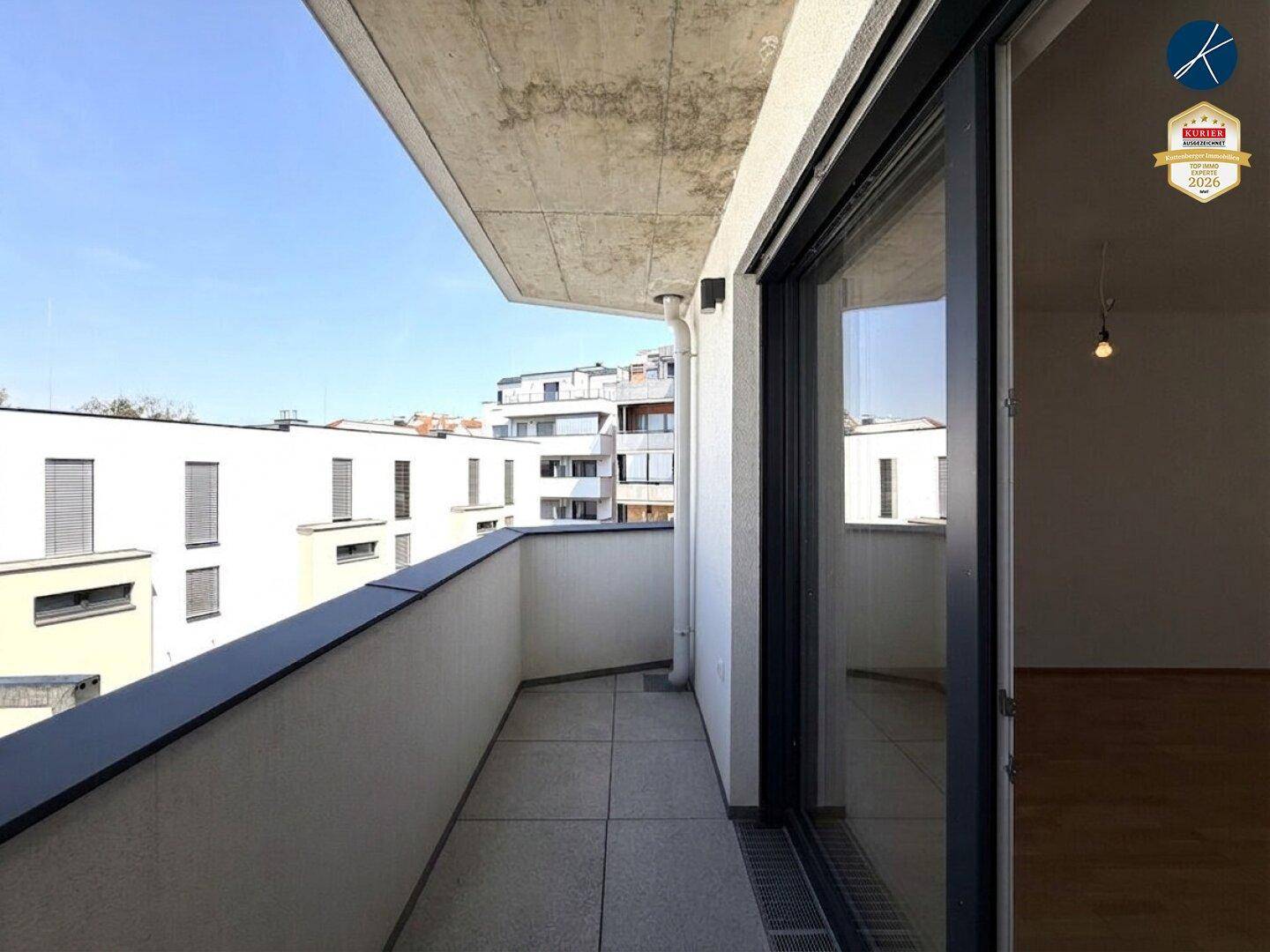 Geräumiger Balkon mit Fliesenboden und Blick auf die umliegenden Gebäude.
