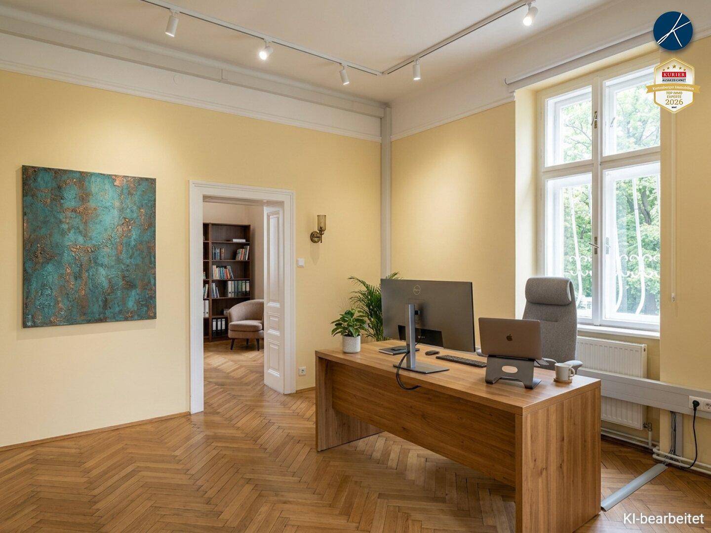 Helles Büro mit Holzschreibtisch, Computer und Fischgrätparkett, angrenzend an einen Raum mit Bücherregalen.