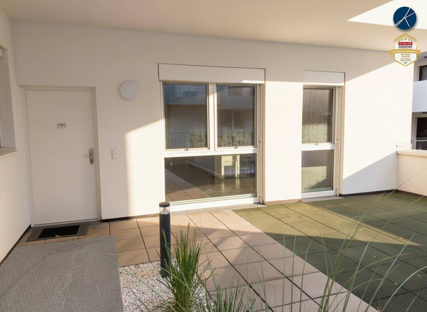 Private Terrasse mit Fliesen und Gummiboden, direktem Zugang zum Innenraum und viel Sonnenlicht.