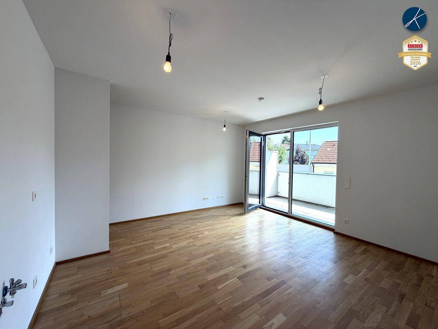 Lichtdurchfluteter Wohnbereich mit Holzboden und direktem Zugang zum Außenbereich, perfekt für offenes Wohnen.