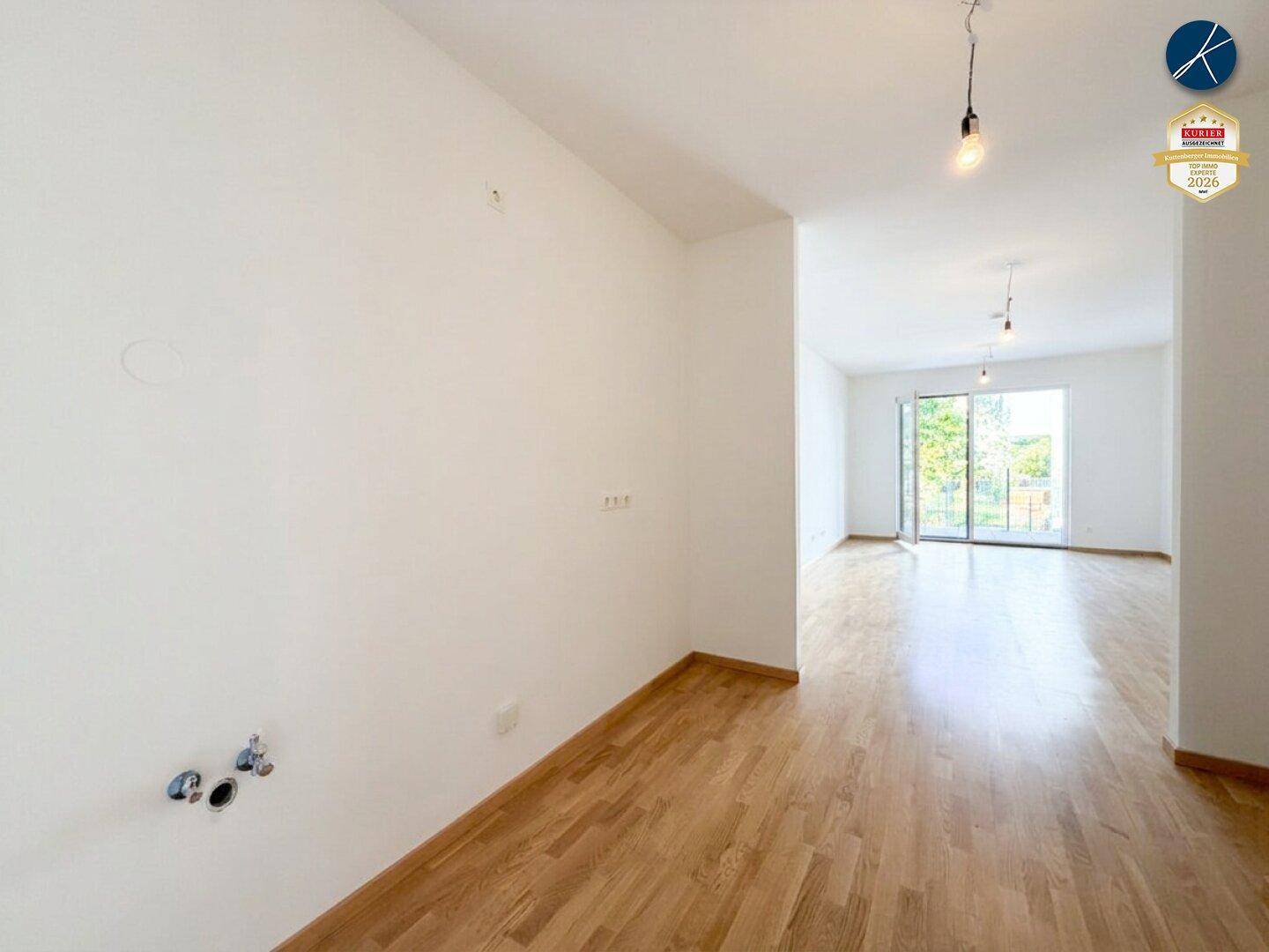 Offener Küchenbereich mit Parkettboden und Anschlüssen für eine Einbauküche.