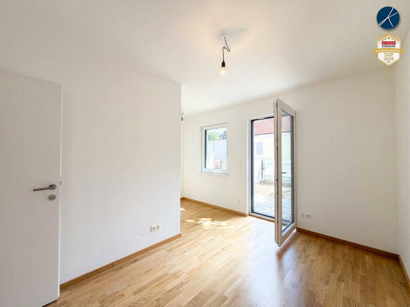Helles Schlafzimmer mit Parkettboden und direktem Zugang zu einem Außenbereich.