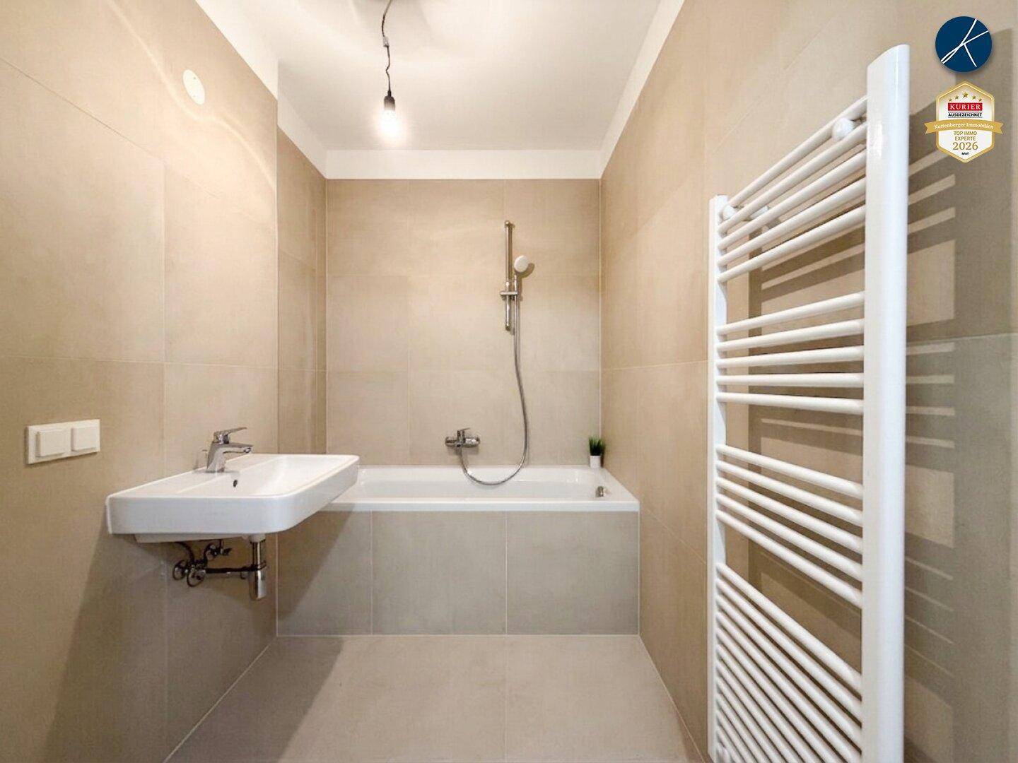 Modernes Badezimmer mit Badewanne, Waschbecken und beheiztem Handtuchhalter.