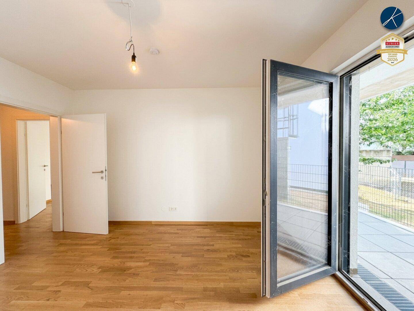 Lichtdurchflutetes Wohnzimmer mit Eichenparkett und breitem Zugang zur Terrasse.