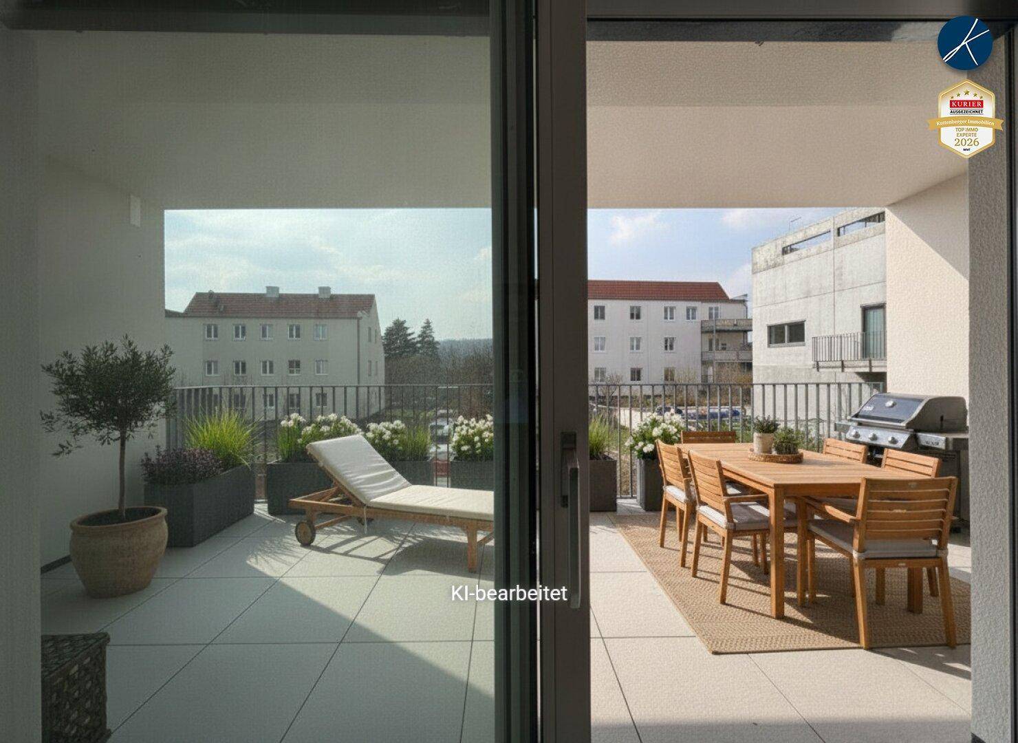 Blick vom Innenraum auf den möblierten Balkon mit Esstisch und Liegestuhl.