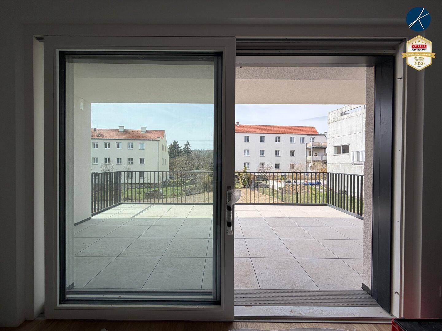 Innenansicht mit großzügiger Schiebetür, die zum gefliesten Balkon mit Weitblick führt.