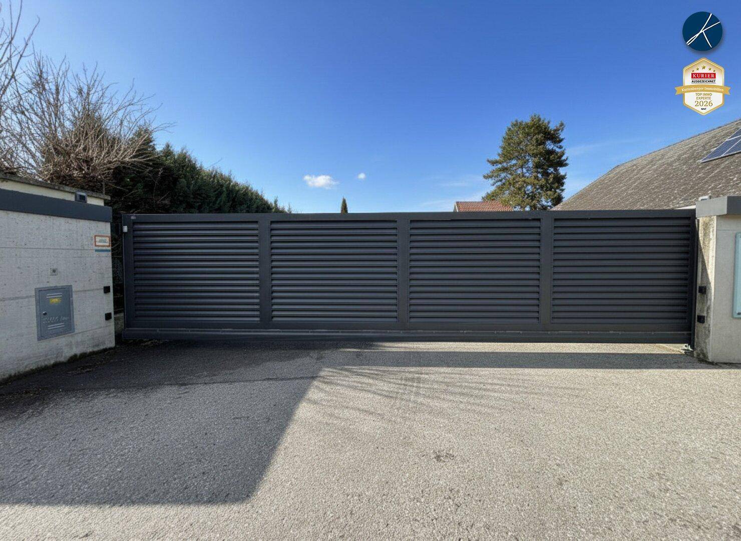 Große, moderne Schiebetor-Anlage aus Metall, die den Zugang zum Grundstück sichert.