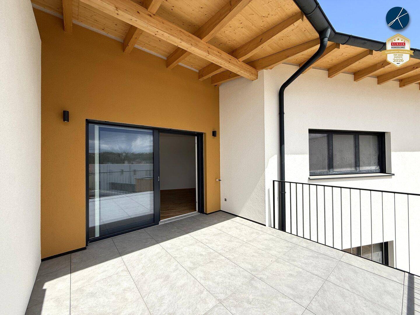 Überdachter Balkon mit Fliesenboden und Holzbalken, ideal für entspannte Stunden im Freien.