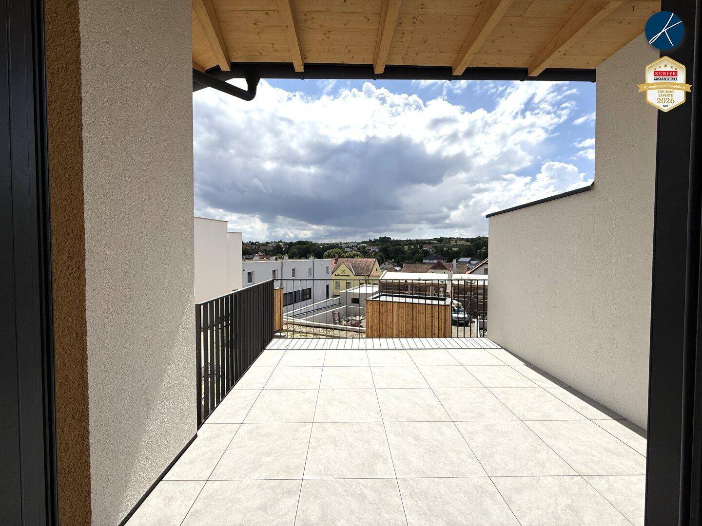 Weitläufiger Balkon mit Fliesenboden und weitem Blick über die Dächer der Umgebung.