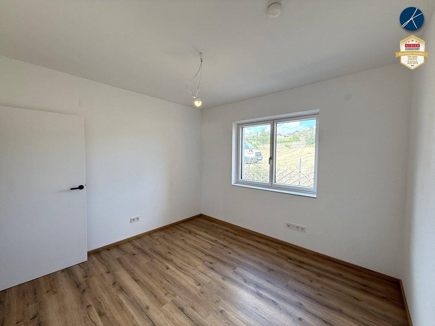 Helles Schlafzimmer mit Laminatboden und großem Fenster, bietet viel Tageslicht.
