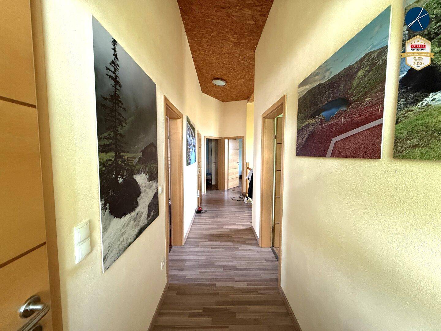 Heller Flur mit Holzboden, OSB-Decke und dekorativen Wandbildern.